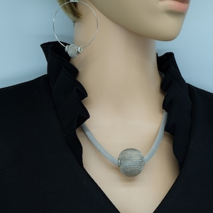 May include: A silver mesh necklace with a large, round, silver mesh pendant.