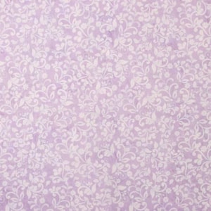 May include: A close-up of a light purple fabric with a delicate floral pattern. The design features white, swirling vines and small flowers, creating a soft, textured appearance. The overall aesthetic is vintage and romantic.