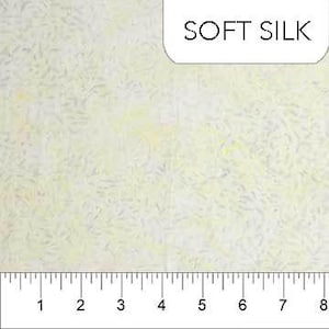 May include: Off-white fabric with a subtle, textured pattern and the text "SOFT SILK" in the upper right corner. A ruler is at the bottom, showing measurements in inches. The fabric has a delicate, almost ethereal appearance.