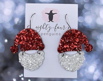 May include: Red and white glitter Santa earrings with silver hooks. The earrings are labeled "eighty-four penguins".