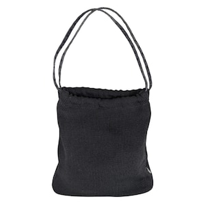 May include: Black knit bucket bag with drawstring closure and matching handles. The bag has a textured appearance and a small tag on the side. The handles are a darker color with a subtle pattern.