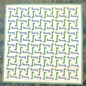 May include: A white quilt with a green and blue geometric pattern. The pattern is made up of repeating squares and rectangles.
