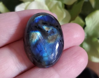 May include: A dark blue oval-shaped labradorite gemstone with iridescent flashes of green and gold.
