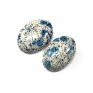 May include: Two oval-shaped blue and white speckled stones. The stones are polished and have a smooth surface.