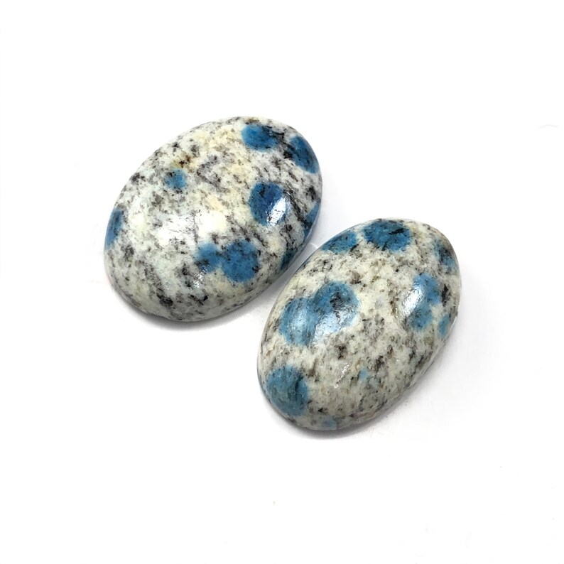 May include: Two oval-shaped blue and white speckled stones. The stones are polished and have a smooth surface.