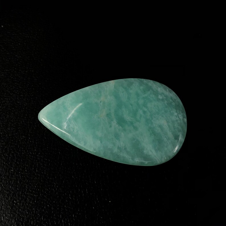Pu&ograve; includere: Una pietra preziosa di acquamarina di colore blu chiaro a forma di lacrima, con una superficie liscia e lucida.