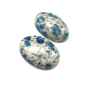 May include: Two oval-shaped blue and white speckled stones. The stones have a smooth, polished finish.
