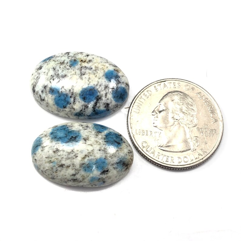 May include: Two oval-shaped blue and white speckled stones, each about the size of a US quarter.