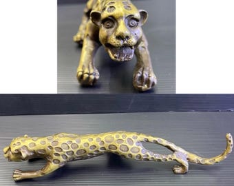 May include: Two bronze leopard sculptures. One is a crouching pose with an open mouth, the other is a long, stretched-out pose. Both have detailed spots and are made of a metallic material.