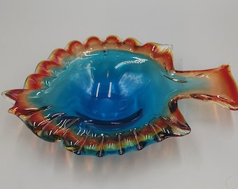 May include: A glass fish-shaped dish with a blue interior and orange, red, and yellow accents.