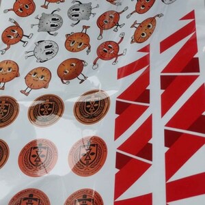 May include: A sheet of stickers featuring cartoon clocks with various facial expressions. The stickers are arranged in a random pattern. The sheet also includes several circular stickers with the text "Time Variance Authority" and a sword and shield logo.