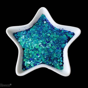 Puede incluir: Un plato blanco en forma de estrella lleno de purpurina azul y verde.