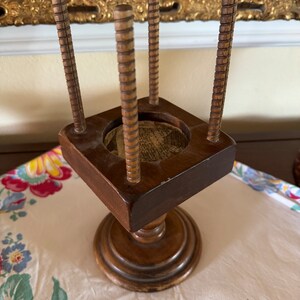May include: A wooden stand with four spindles and a square top. The stand has a turned base and is made of dark wood.