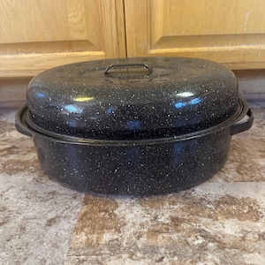 May include: Black enamel oval roaster with a lid and two handles. The roaster has a speckled finish.