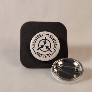 May include: A white button featuring a black and white logo that reads "Secure, Contain, Protect" and a black triangle with three arrows pointing in different directions. The button is set against a black background and has a silver pin back.
