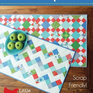 May include: Two colorful patchwork table runners, one with a chevron pattern and the other with a diamond pattern. The runners are made from scraps of fabric in shades of red, blue, green, and white. The text "Scrap Friendly!" is printed on the image. The text "Little Cluck Cluck Sew" is also printed on the image.