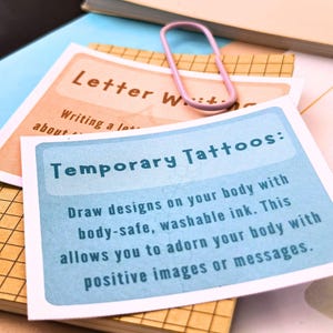 a close-up view of a temporary tattoo card with instructions on how to draw designs on one's body using washable ink.