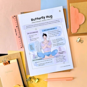 May include: A printed guide titled "Butterfly Hug" with instructions for a self-soothing technique. The guide is on a white sheet with illustrations and text, surrounded by stationery items like a ruler, notepads, and paper clips.