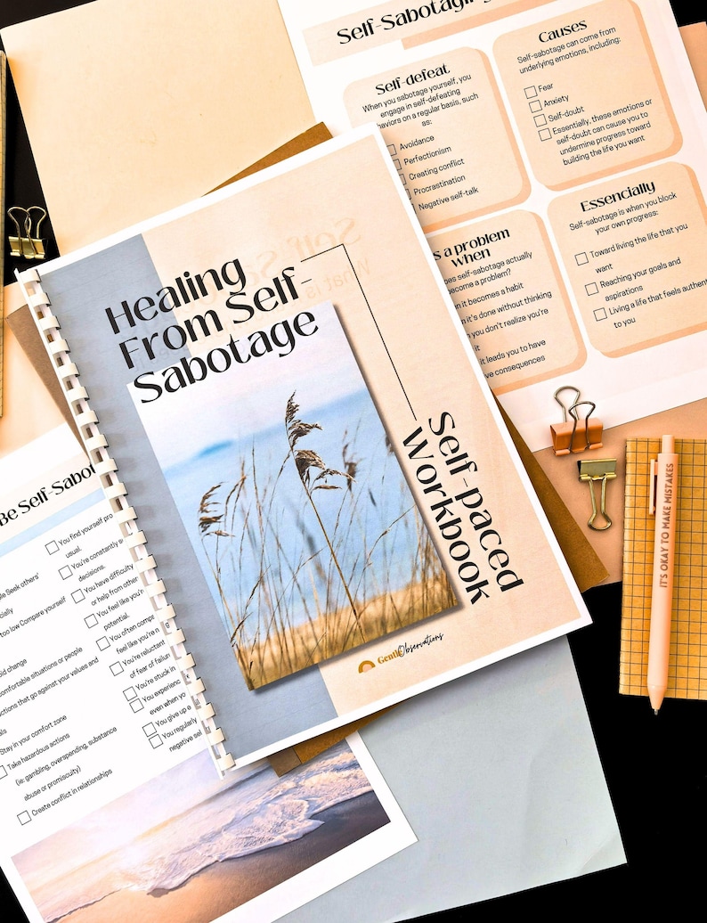 a self-healing workbook titled "Healing From Self-Sabotage" with a list of self-healing techniques and a calming nature scene. The workbook is surrounded by other materials, including a pen, a stapler, and a piece of paper.