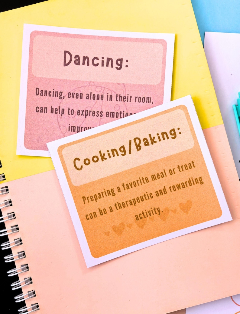 two cards with text on them, placed on a yellow and pink notebook.