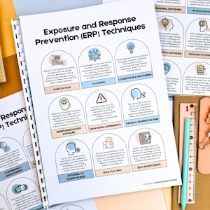May include: A spiral-bound notebook with the title "Exposure and Response Prevention (ERP) Techniques" is open, displaying various techniques for managing anxiety and OCD. A teal pen and a paperclip rest on a brown surface next to the notebook.