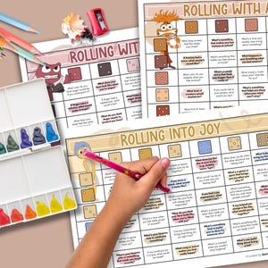 May include: A watercolor paint set, colored pencils, and three printable worksheets titled "Rolling With Anxiety" and "Rolling Into Joy" are displayed. A hand is holding a pink pencil over one of the worksheets. The worksheets have a grid format with questions.