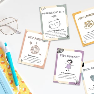 A neatly arranged stack of Somatic Therapy Coping Skill Cards for kids, featuring various emotional regulation techniques, placed on a white desk alongside a notebook and pen.