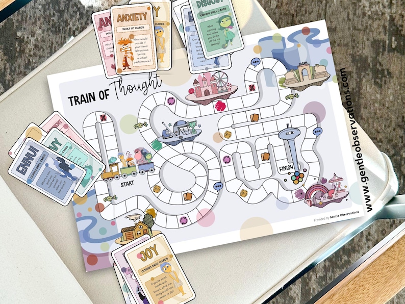 May include: A board game titled "Train of Thought" with a colorful illustrated game board and cards. The game board features a path with various illustrations, including a train, a ferris wheel, and a castle. Cards with words like "Anxiety" and "Joy" are included.