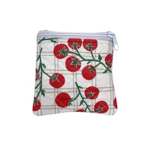 May include: A quilted fabric pouch featuring a white background with a light gray grid pattern and a repeating print of red tomatoes on green vines. The square-shaped accessory includes a light gray zipper closure along the top edge.