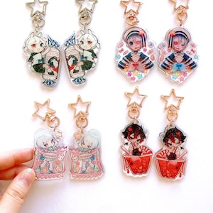 Puede incluir: Seis llaveros coloridos con personajes de estilo anime. Cada llavero tiene un diseño diferente y presenta un dije de acrílico transparente con un anillo de metal y un cierre dorado.