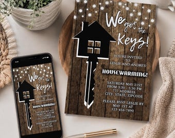 May include: A housewarming invitation card and a smartphone displaying the same invitation, both featuring a rustic wood background, white string lights, and a black house-shaped key graphic with the text We got the Keys! HOUSEWARMING!