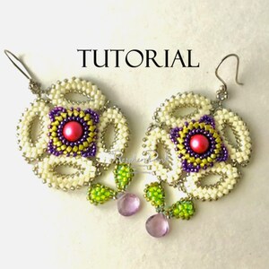 Könnte beinhalten: Ein Paar Perlenohrringe mit einem Blumenmuster. Die Ohrringe sind aus weißen, violetten, grünen und gelben Perlen gefertigt. Die Ohrringe haben eine rosa Perle in der Mitte des Blumenmusters. Die Ohrringe hängen an silbernen Haken.