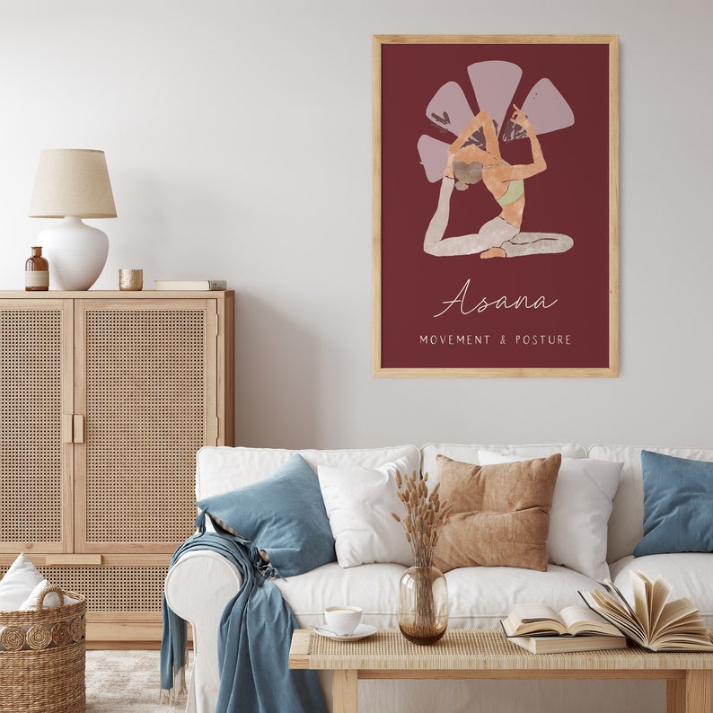 May include: A framed art print featuring a yoga pose illustration. The artwork depicts a person in a seated backbend pose against a deep red background. The word "Asana" is written in cursive, with "Movement & Posture" below.
