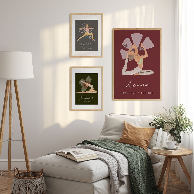 May include: Three framed yoga art prints hang on a white wall. The prints feature illustrations of yoga poses with text. The top print says "Yama" and the bottom print says "Niyama". The largest print says "Asana" and "Movement & Posture".