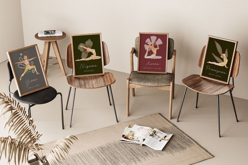 May include: Four framed yoga art prints, each featuring a different pose and corresponding text. The prints are displayed on various chairs, with a neutral-toned rug and a small side table in the background. The color palette includes muted greens, reds, and yellows.