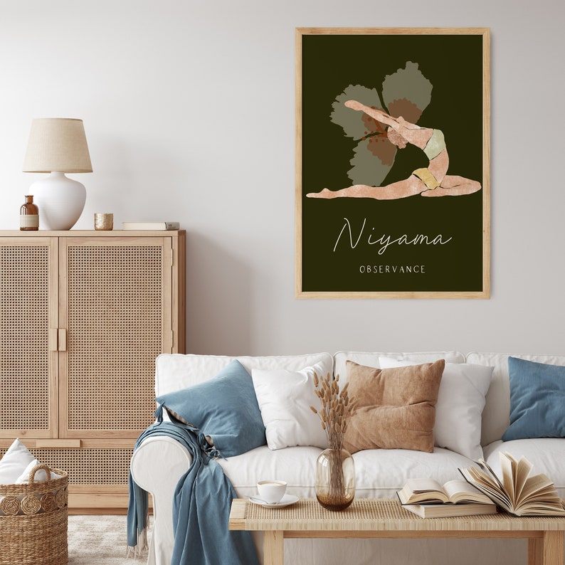 May include: A framed art print featuring a yoga pose illustration. The artwork depicts a figure in a backbend, with the word "Niyama" and "Observance" in a script font. The background is a dark green, and the frame is light brown.