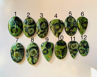 Puede incluir: Doce piedras preciosas pulidas de diversas formas, incluyendo óvalos y lágrimas. Las piedras presentan un patrón arremolinado de verde oscuro y negro, con toques de verde claro y amarillo. Las piedras preciosas están numeradas del 1 al 12.