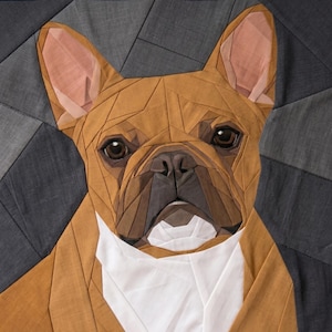 Puede incluir: Un retrato de tela tipo quilt de un bulldog francés con piezas geométricas en tonos tostado, marrón y blanco. El perro tiene orejas grandes y erguidas, ojos marrón oscuro y un hocico oscuro, sobre un fondo de paneles de tela gris oscuro.