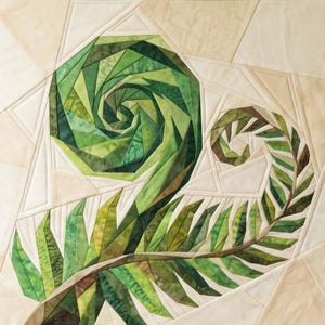 Op de afbeelding: Een stoffen quiltblok met een paper-pieced ontwerp van een varenblad. De centrale spiraal en het uitlopende blad zijn opgebouwd uit diverse tinten groen en bruin textiel, geplaatst tegen een achtergrond van crèmekleurige geometrische panelen.