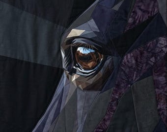 May include: A fabric wall hanging featuring a geometric pieced quilt design of a horse eye. The composition uses various shades of black, charcoal, and deep purple fabric pieces with visible stitching lines to form the detailed eye structure.