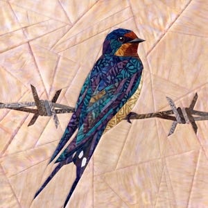 May include: A fabric quilt wall hanging featuring a pieced swallow bird perched on a strand of barbed wire. The bird is constructed from various blue, purple, and gold patterned fabric scraps. The background consists of light tan geometric shapes.