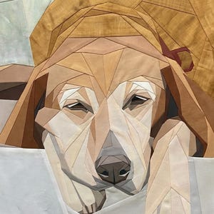 May include: A fabric quilt wall hanging featuring a geometric, pieced-together portrait of a dog. The dog is rendered in various shades of tan, brown, and cream fabric, with a dark brown nose and eyes, resting its head on a white fabric surface.
