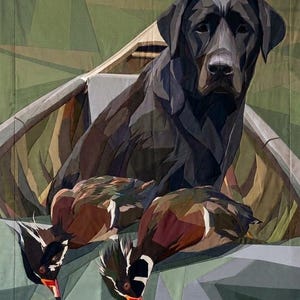 May include: A fabric quilt wall hanging featuring a pieced geometric design of a black Labrador retriever sitting in a wooden boat with two wood ducks in the foreground. The composition uses various shades of green, brown, black, and white fabric.