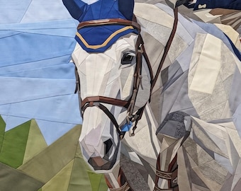 May include: A fabric quilt wall hanging depicting a white horse with a blue ear bonnet and brown leather bridle. The horse is shown in motion with a rider in a navy blue jacket. The background features geometric shapes in blue, green, and white.