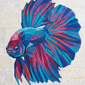 May include: A colorful, geometric quilt featuring a betta fish design. The fish is rendered in shades of blue, purple, and orange, with a detailed, angular pattern. The background is a light, patterned fabric.