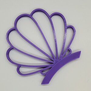 May include: A purple plastic seashell-shaped cookie cutter.
