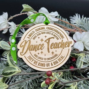 Puede incluir: Un adorno de madera con fondo marr&oacute;n y texto blanco. El texto dice "A multi-tasking, choreographing rock star who lives to inspire Dance Teacher and loves to encourage. They're kind of a big deal."