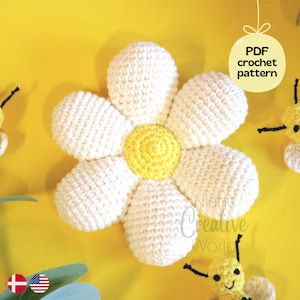 May include: A white crocheted daisy flower with a yellow center. The flower is on a yellow background with two small crocheted bees. The image includes the text "PDF crochet pattern".
