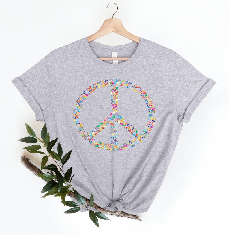 May include: A heather gray t-shirt with a peace sign made of colorful leaves. The peace sign is centered on the shirt.