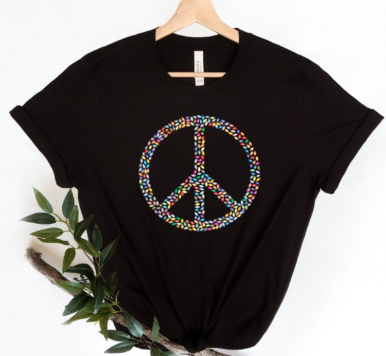May include: Black t-shirt with a peace sign made of colorful leaves.